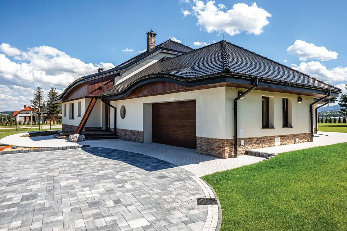 Podjazd wykonany z bruku betonowego w naturalnych odcieniach przypominających kamień Podjazd wykonany z bruku betonowego w naturalnych odcieniach przypominających kamień